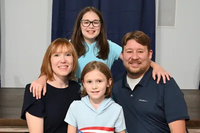 Nick's family: his wife and two daughters dressed in shades of blue.