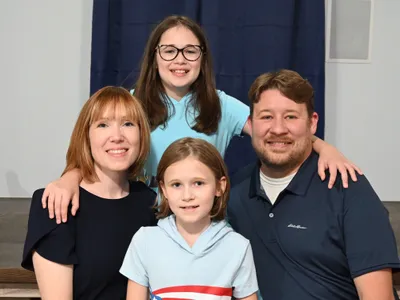 Nick's family: his wife and two daughters dressed in shades of blue.